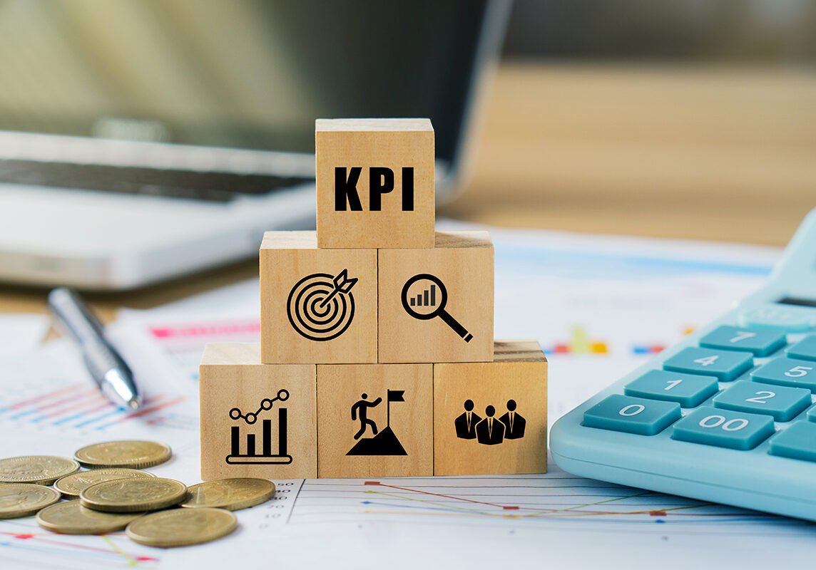 KPI, Key Performance Indicator.KPI icon on wooded cube with paperwork calculator and coin on a board room table. business goals, performance results and indicators.